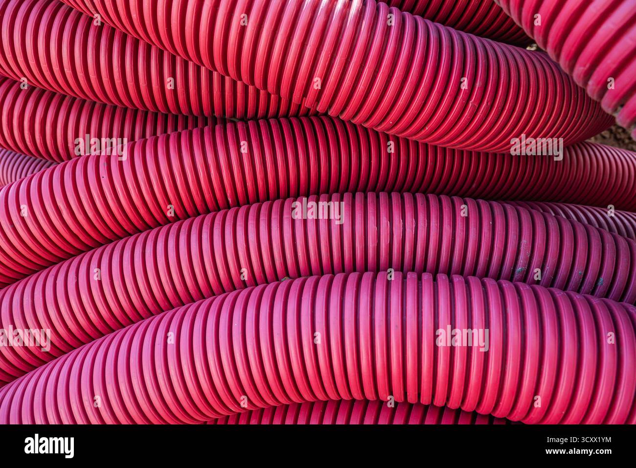 Pile di tubi flessibili rossi per la posa di cavi, primo piano Foto Stock