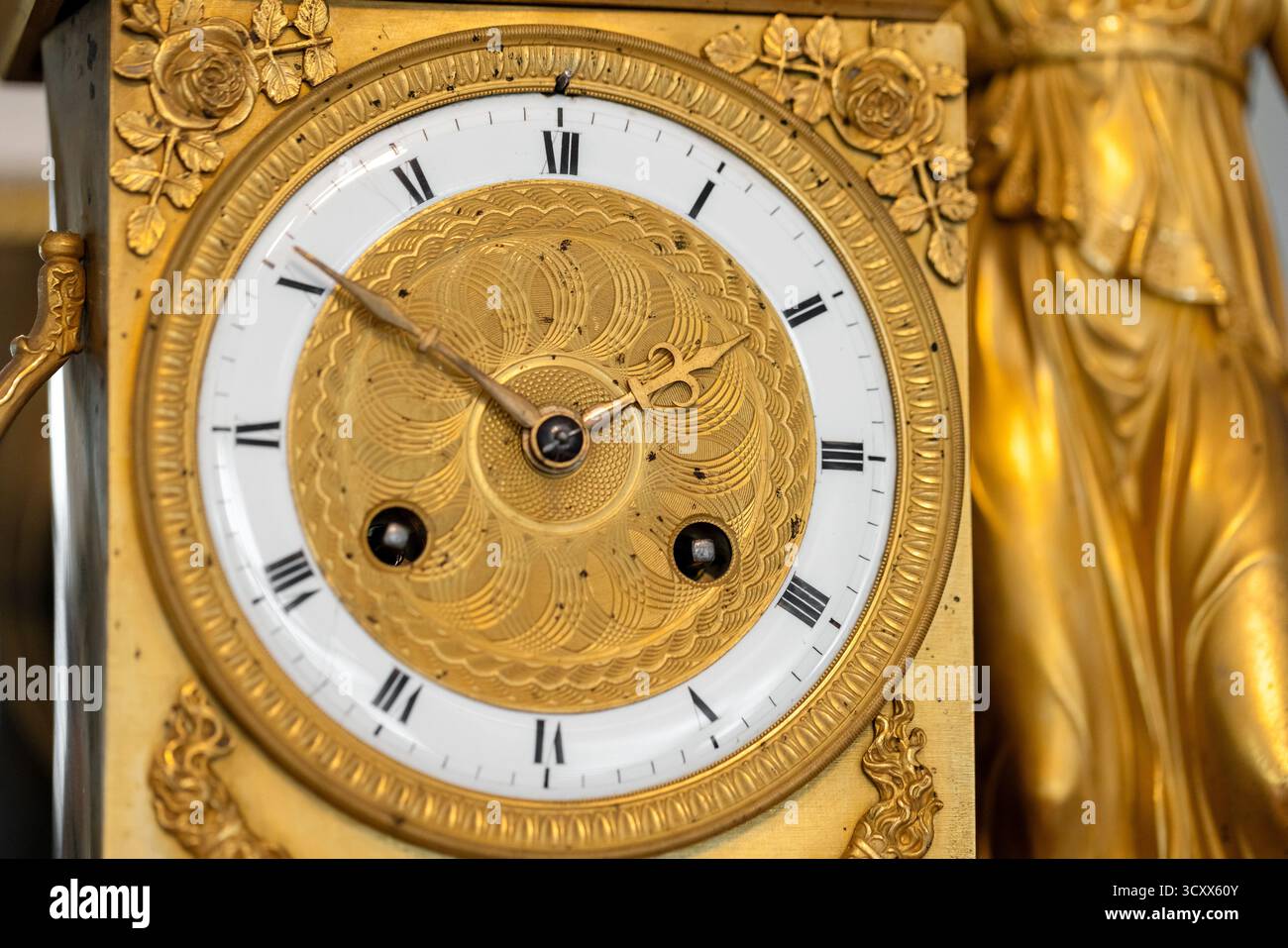 Lussuoso orologio in oro con quadrante inciso, numeri romani e bordi floreali decorati. Un raffinato centrotavola che evoca la classica maestria artigianale e tim Foto Stock