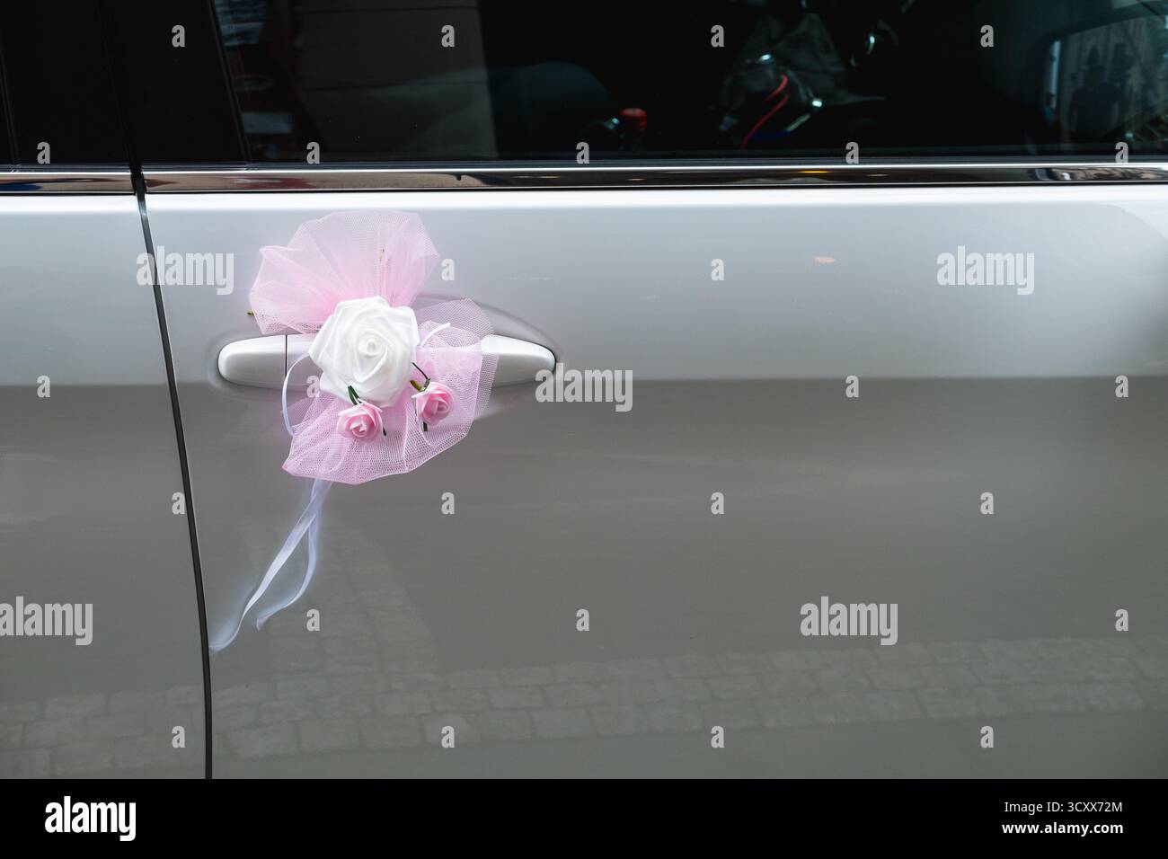 Auto da sposa con rosa bianca e tulle rosa sulla maniglia della portiera Foto Stock