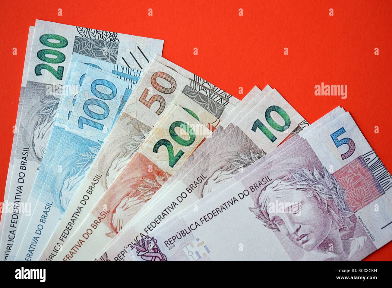 Primo piano di banconote brasiliane del Reais in grande quantità sul tavolo rosso. Una pila di banconote in valuta reale del Brasile. Concetto finanziario e bancario Foto Stock