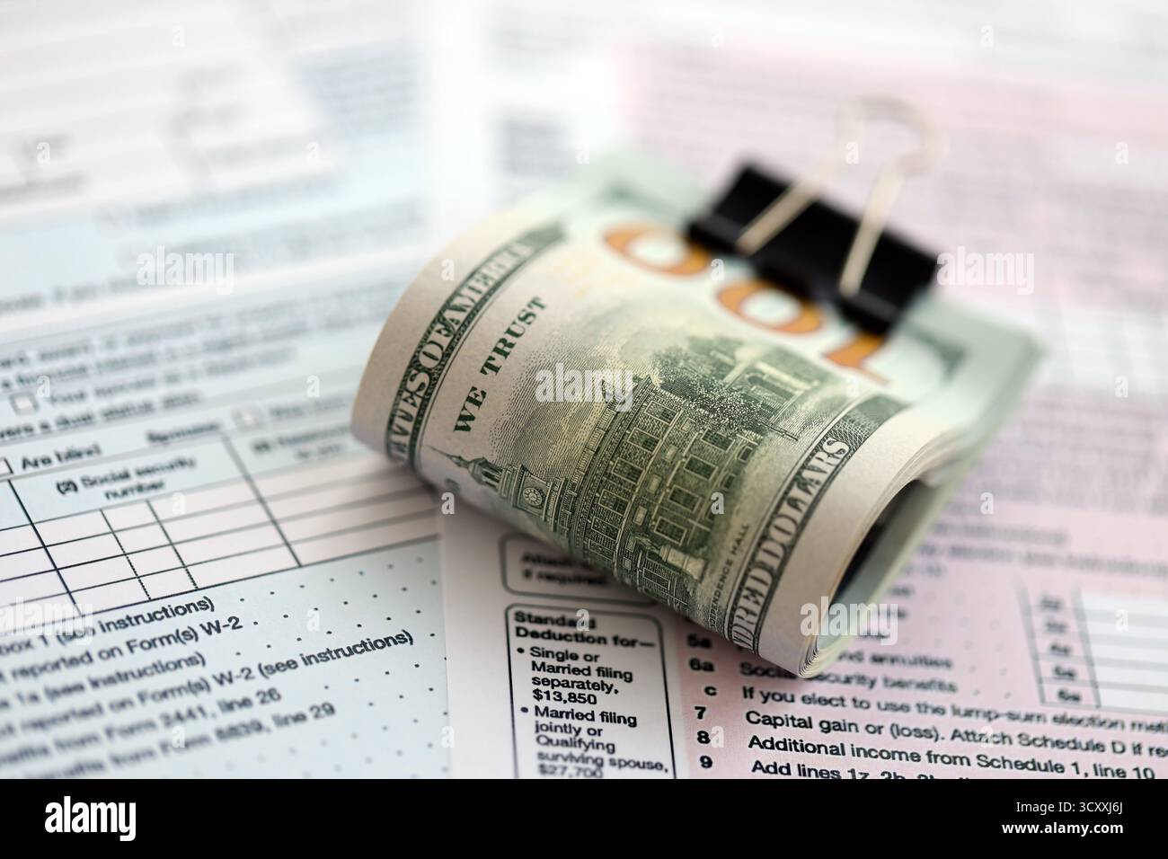 Grande quantità di banconote in dollari statunitensi in banconote e banconote con 1040 modulo di dichiarazione dei redditi individuale. Concetto di tassazione e contabilità in uni Foto Stock