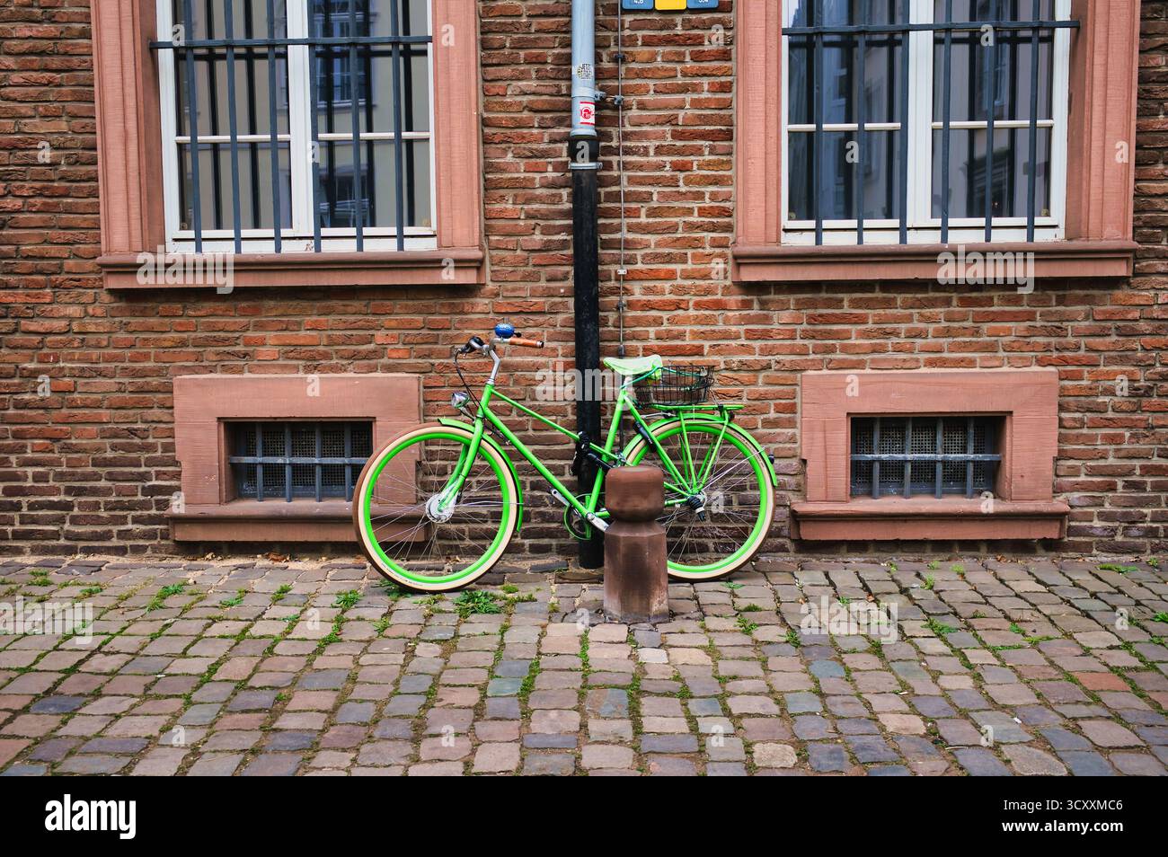 Bicicletta d'epoca verde brillante parcheggiata contro la storica muraglia di mattoni in strada acciottolata nel centro storico di Düsseldorf, Germania Foto Stock