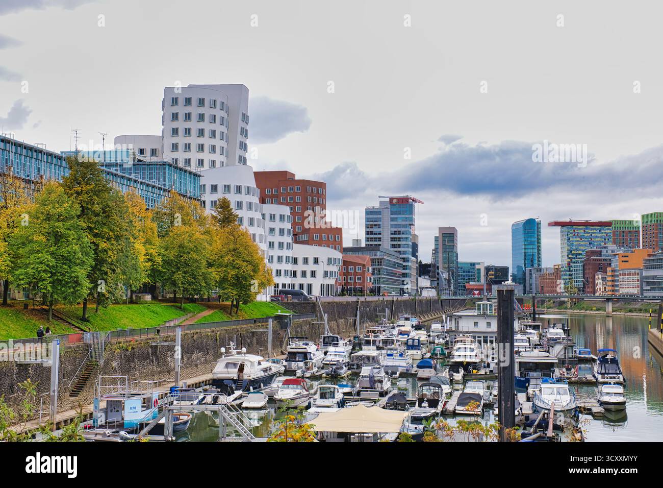 Gehry ha progettato edifici Twisted che si affacciano sulla trafficata Marina con barche attraccate e alberi d'autunno a Düsseldorf in Germania Foto Stock