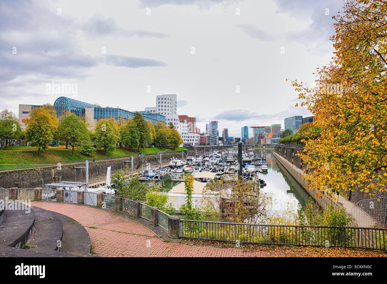 Gehry ha progettato edifici Twisted che si affacciano sulla trafficata Marina con barche attraccate e alberi d'autunno a Düsseldorf in Germania Foto Stock