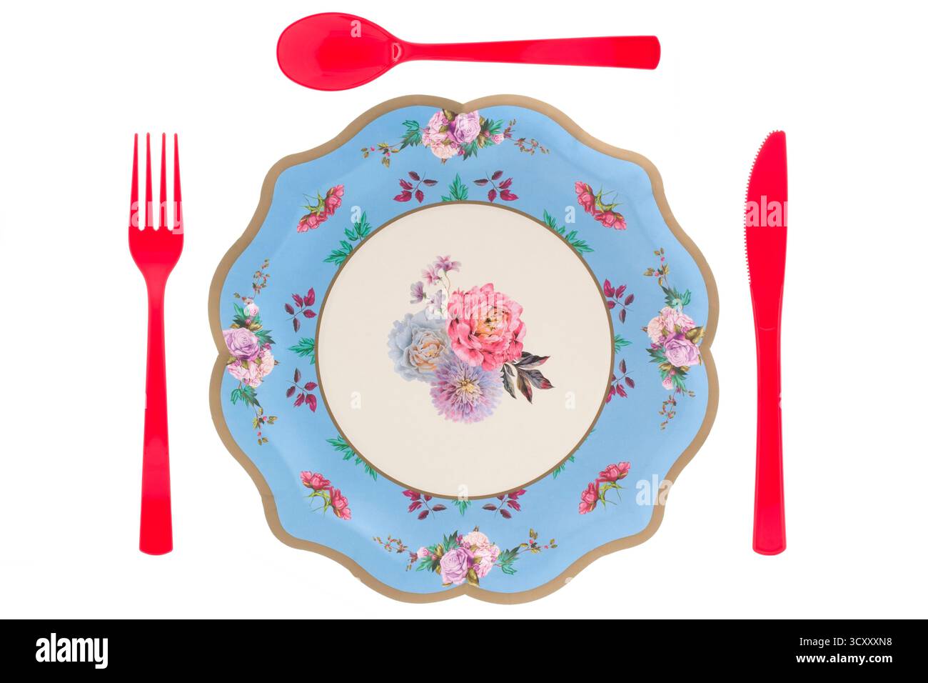 Piatto di carta blu floreale e posate di plastica rossa su sfondo bianco Foto Stock