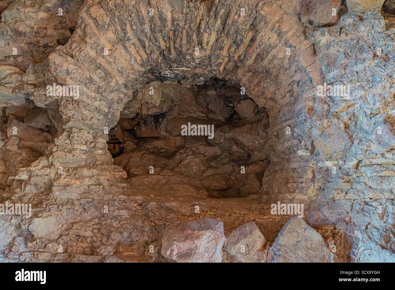 Un'antica arcata in pietra che conduce a un edificio storico o a una grotta sotterranea, evocando mistero e intrighi Foto Stock