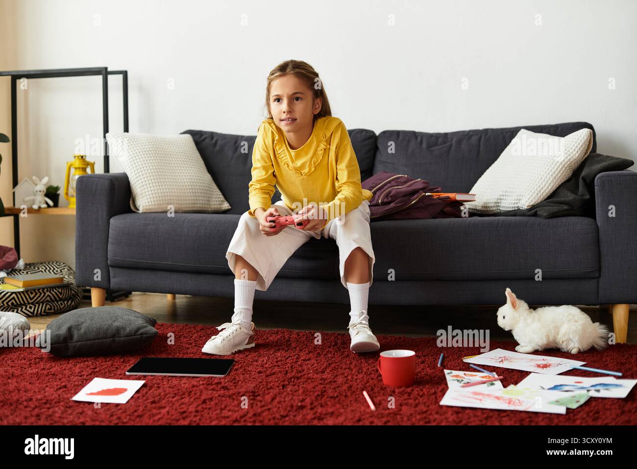 Una ragazza Gen Alpha si diverte a stare a casa giocando ai videogame sul divano. Foto Stock