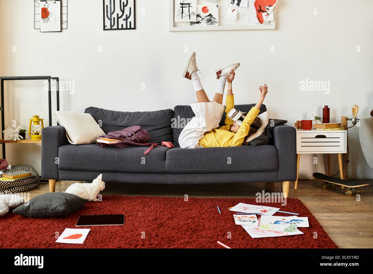 Una bambina alfa si rilassa sul divano, gioca ed esprime il suo lato divertente. Foto Stock