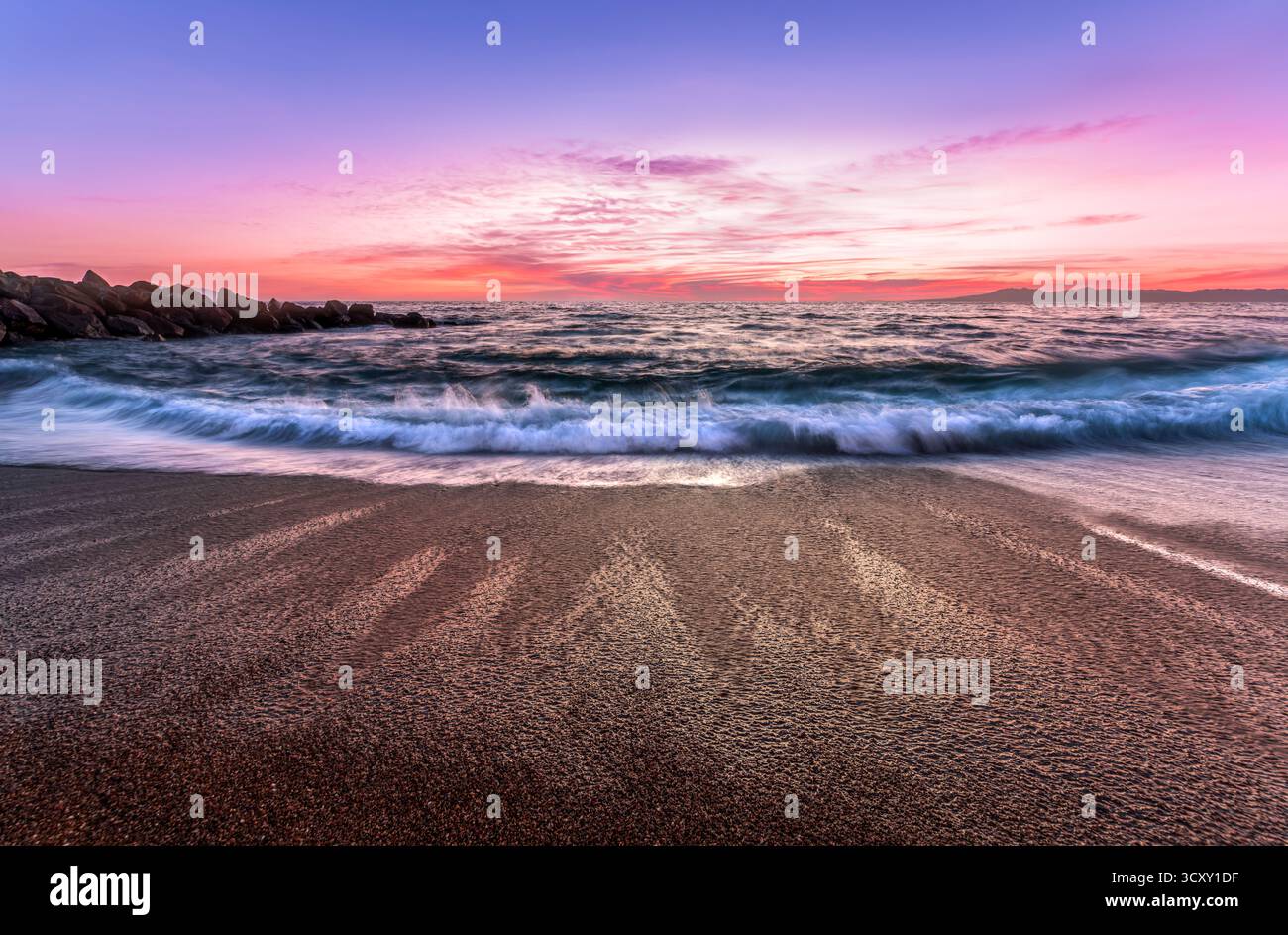 Una colorata alba sull'Oceano con Un'onda dolce che si infrangono sulla costa Foto Stock