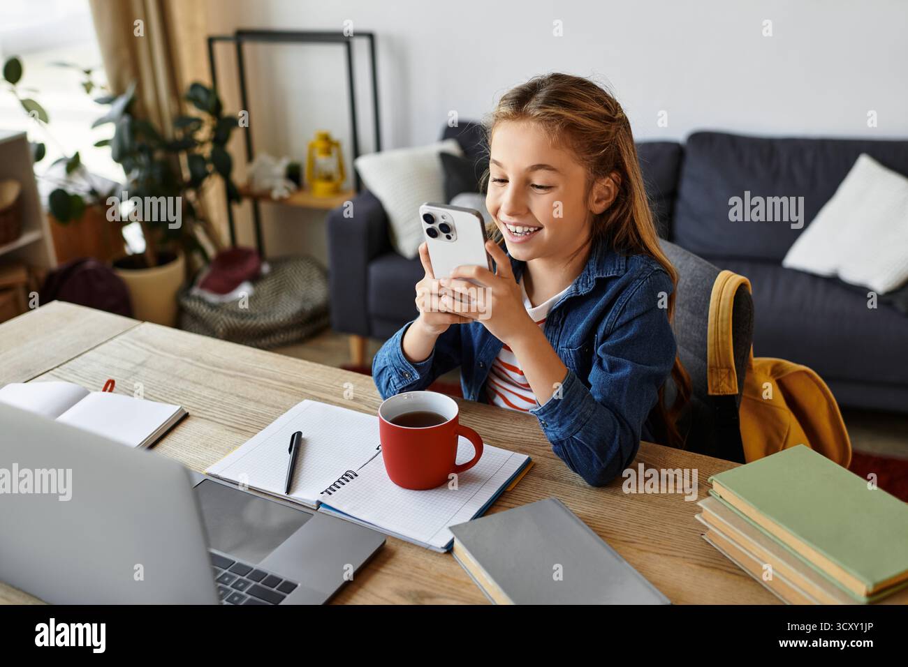 Una ragazza allegra si rilassa a casa, fidanzata con il suo telefono, ragazzo alfa di generazione Foto Stock