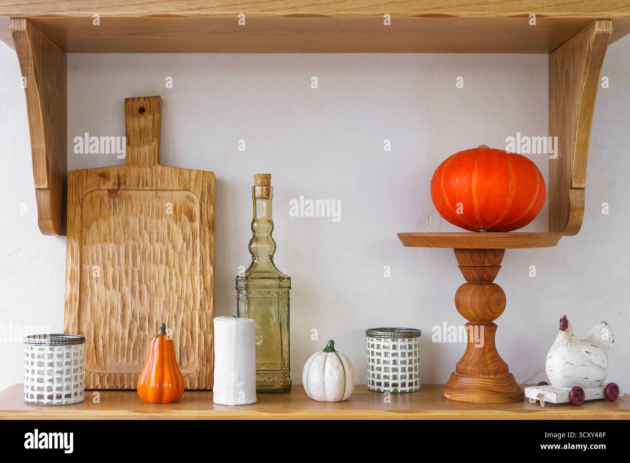 Decorazioni autunnali con zucche e foglie gialle autunnali, decorazioni su scaffali in legno e utensili da cucina rustici. Atmosfera accogliente, perfetta per la stagione Foto Stock