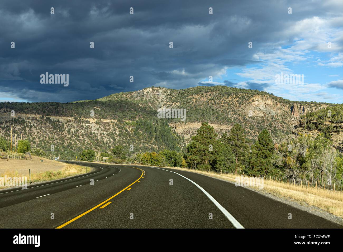 Un'autostrada curva si snoda attraverso le aspre montagne del Colorado occidentale, sotto un cielo nuvoloso. Foto Stock