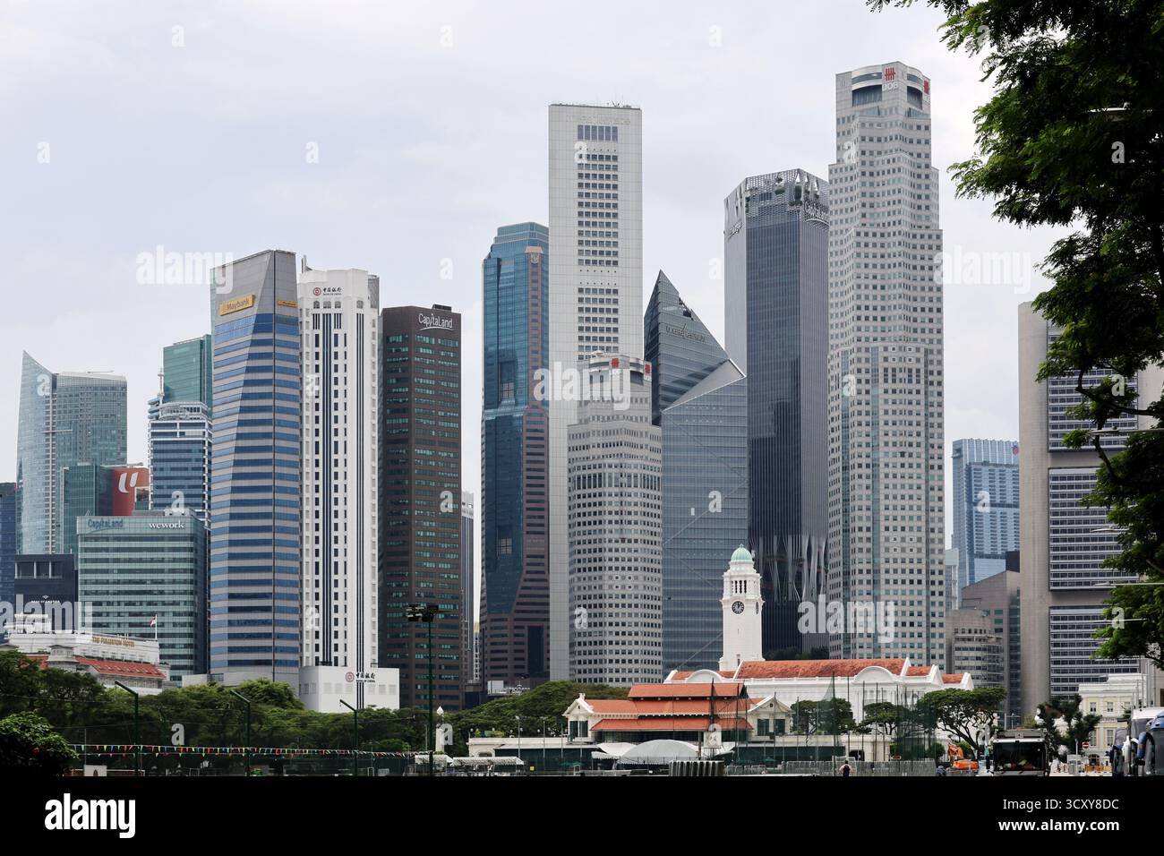 Lo storico Cricket Club Clubhouse e il Victoria Theatre Clocktower di fronte ai grattacieli del quartiere finanziario centrale da Beach Road, Singapore Foto Stock