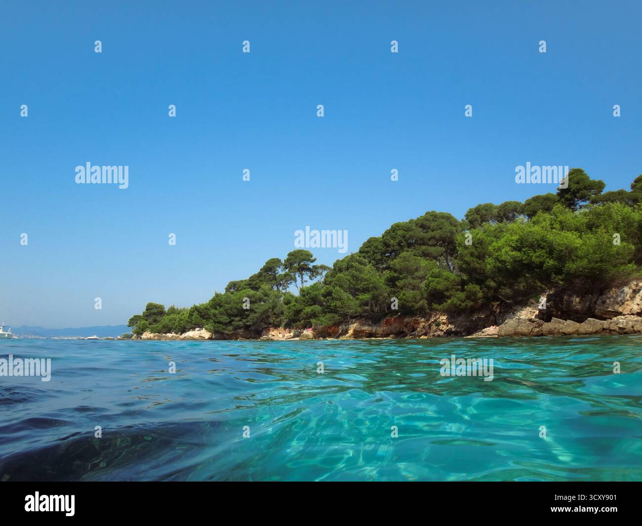 Mare turchese cristallino e costa rocciosa con alberi verdi Foto Stock