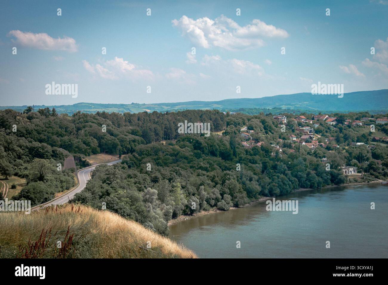 Novi Sad, Serbia. Una vista del fiume Danubio, verdi colline ricoperte di foreste, con una strada che passa attraverso, che conduce ai sobborghi. Foto Stock