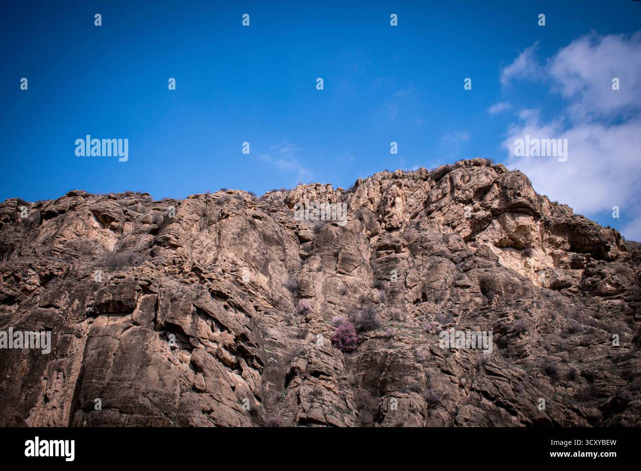 Un paesaggio montano in Armenia con aspre vette rossastre-arancioni che si estendono attraverso l'orizzonte. Foto Stock