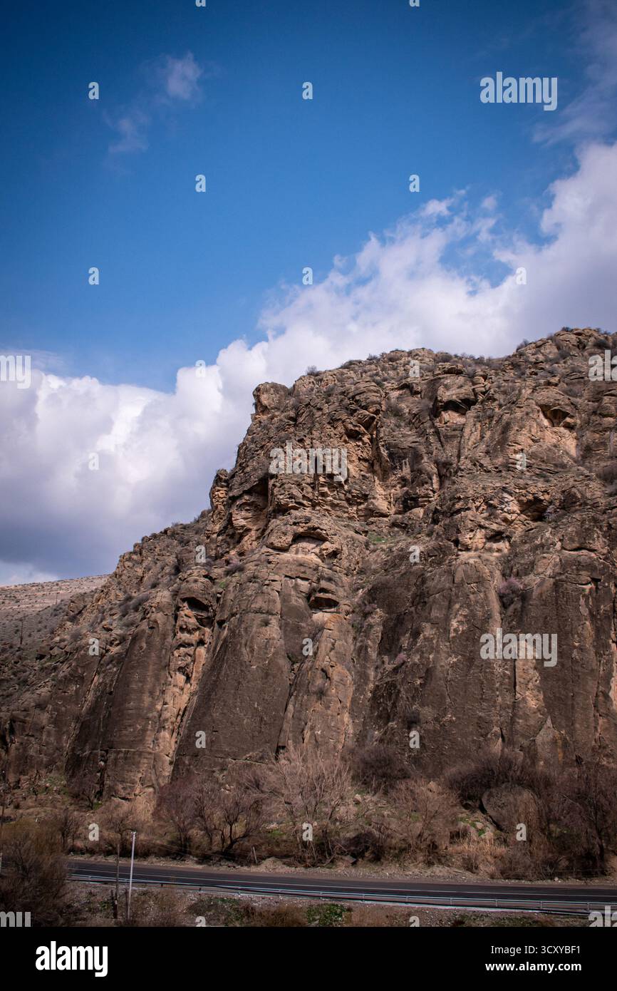 Un paesaggio montano in Armenia con aspre vette rossastre-arancioni che si estendono attraverso l'orizzonte. Foto Stock