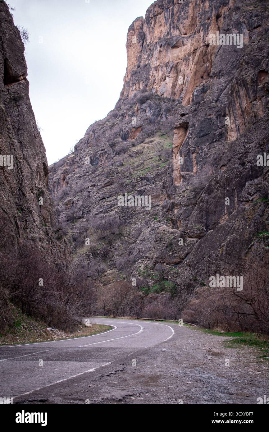 Una strada tortuosa che attraversa uno stretto canyon, fiancheggiata da ripide e aspre scogliere su entrambi i lati. Foto Stock
