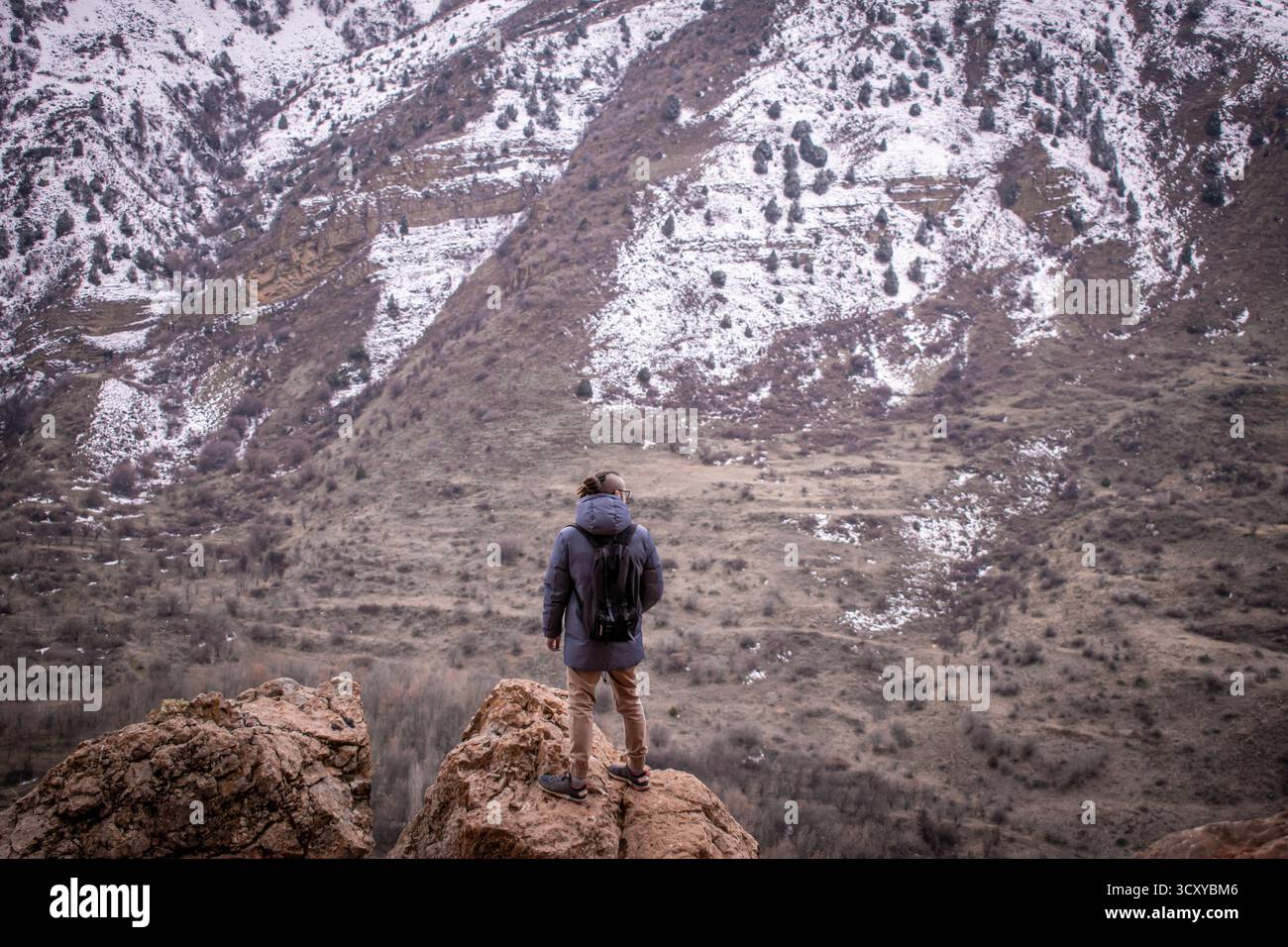 Montagne invernali dell'Armenia, le cui cime sono ricoperte di neve. Una persona con uno zaino sta in cima a una montagna. Foto Stock