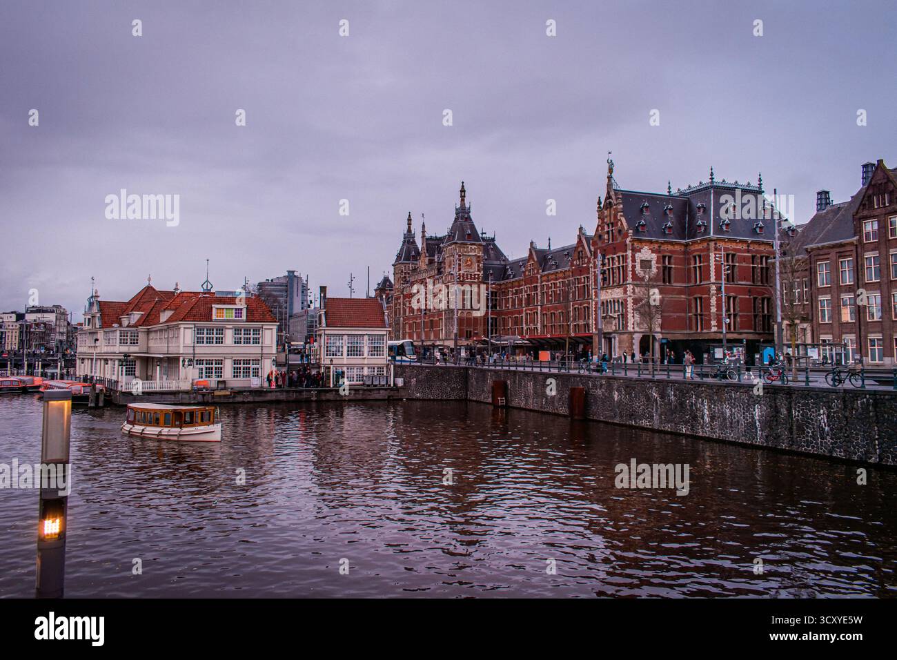 Amsterdam, Paesi Bassi. La splendida architettura della città è allineata alla riva del canale, dove sono ormeggiate barche di varie dimensioni, pronte per la visita turistica. Foto Stock