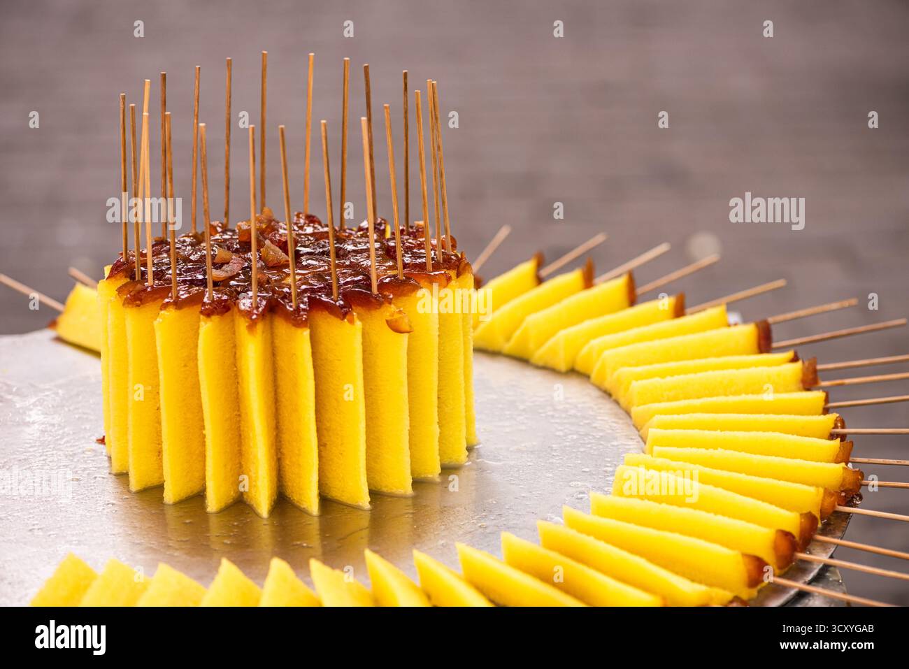 Osmanthus Cake, una torta gialla aromatizzata con fiori profumati e condita con datteri, viene servita sugli spiedini del quartiere musulmano di Xi'an. Foto Stock
