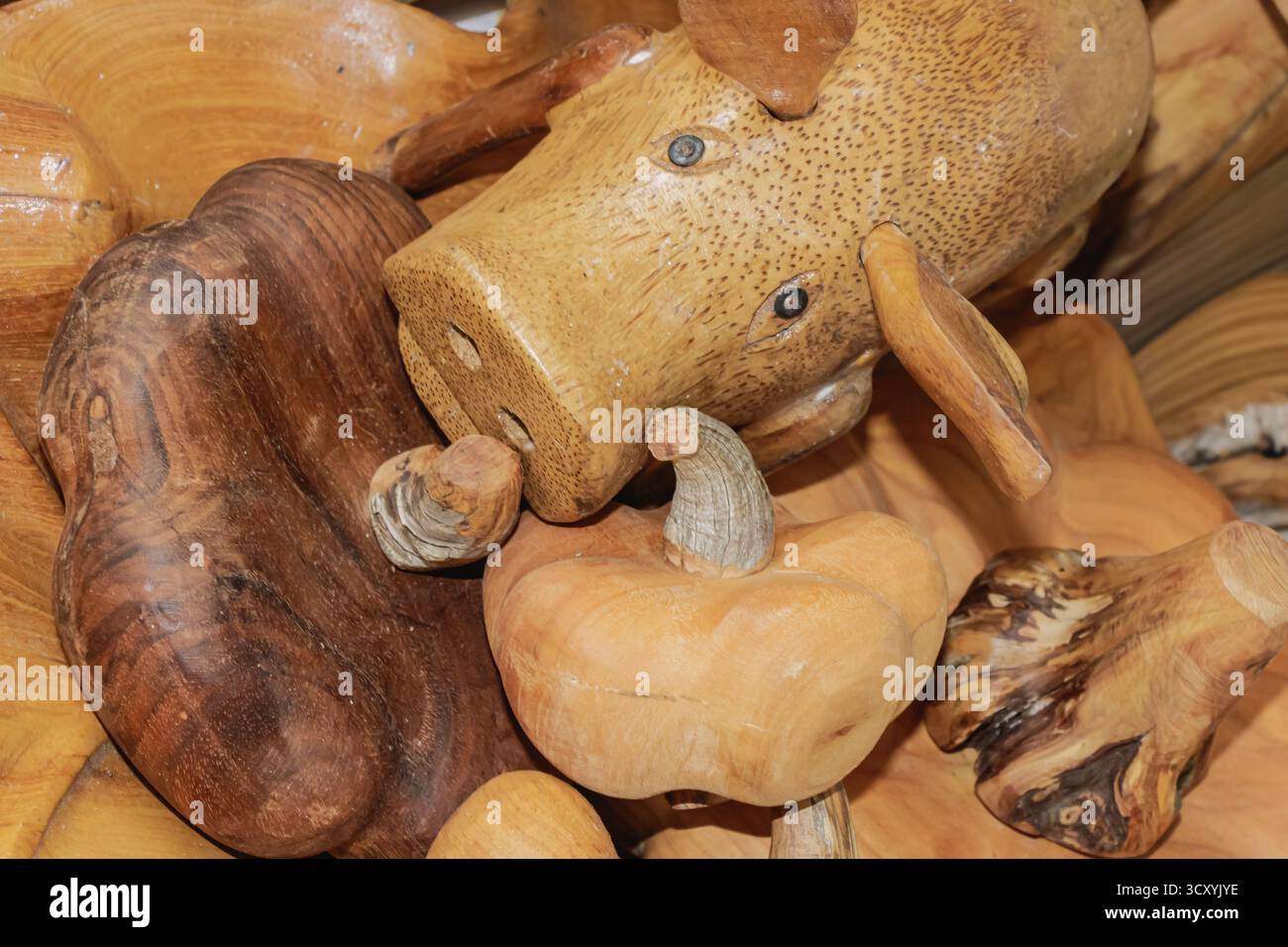 Primo piano di una scultura di maiale in legno fatta a mano circondata da sculture in legno naturale, che mettono in risalto la raffinata maestria artigianale, il design rustico e il calore del nat Foto Stock