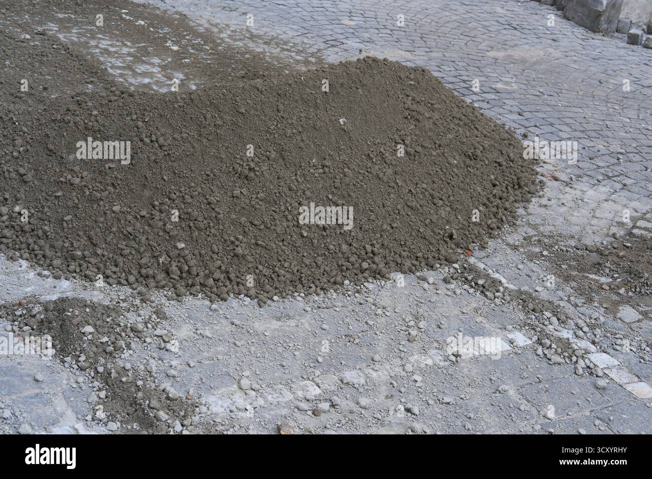 Un mucchio di cemento o sabbia finitrice sulla strada è in fase di ristrutturazione. Materiali di base per edilizia, pavimentazione e architettura paesaggistica Foto Stock