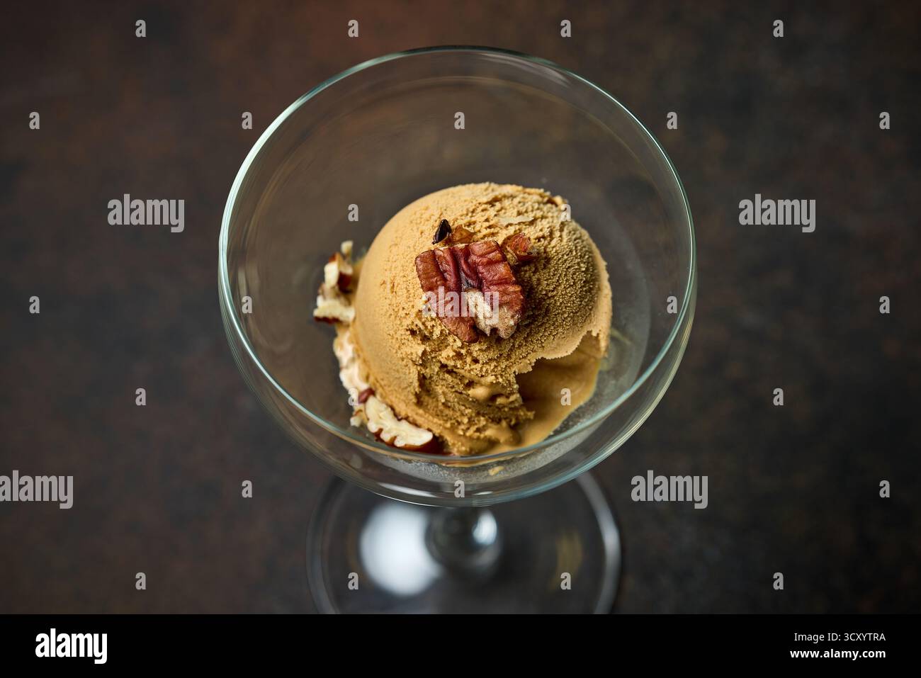 paletta per gelato al caramello con noci servita in vetro su sfondo marrone scuro Foto Stock