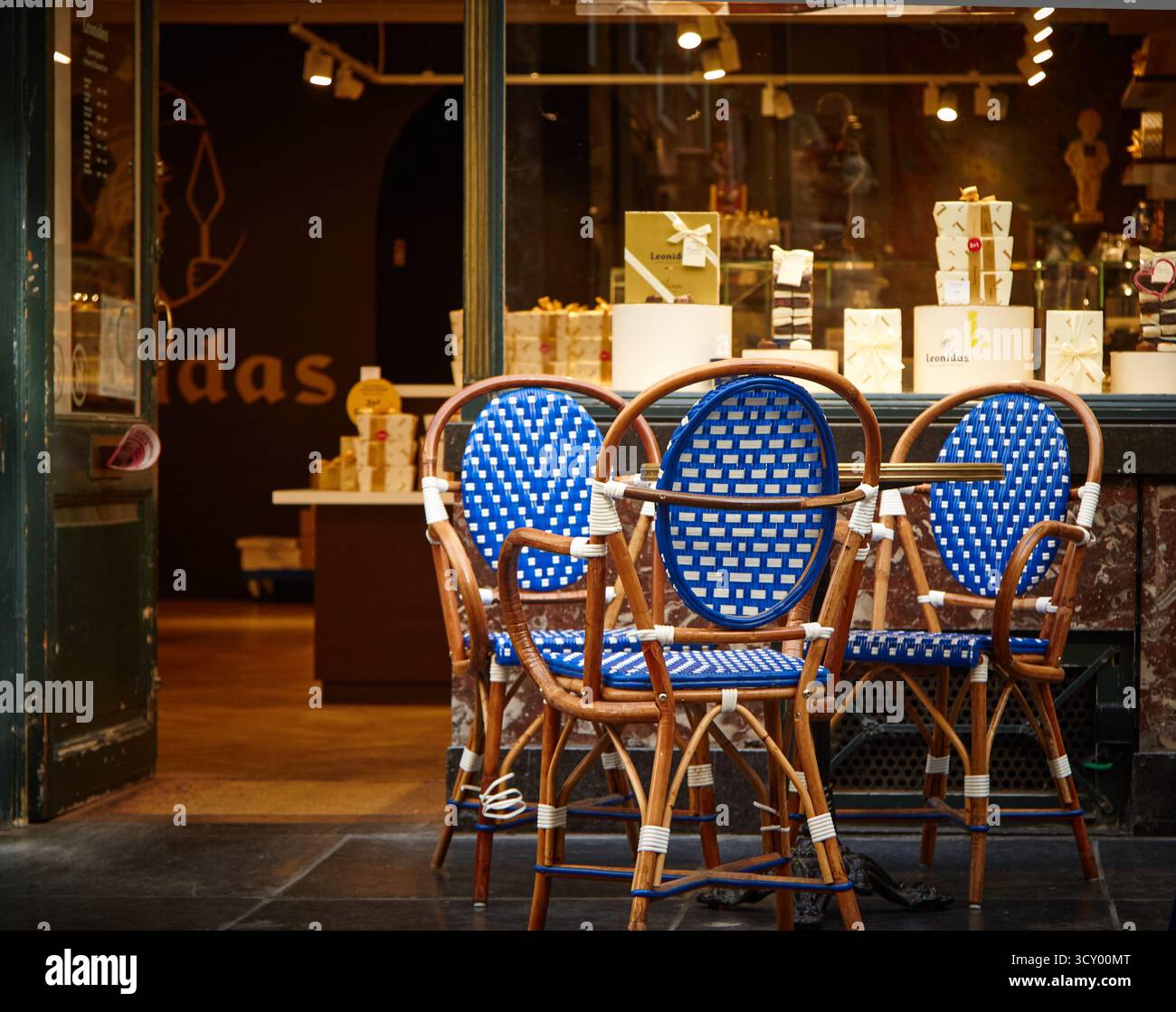 Bruxelles, Belgio - 1° ottobre 2025: Sedie in stile bistrot blu e bianco fuori dalla famosa pasticceria della Galerie Saint-Hubert di Bruxelles offrono un Foto Stock