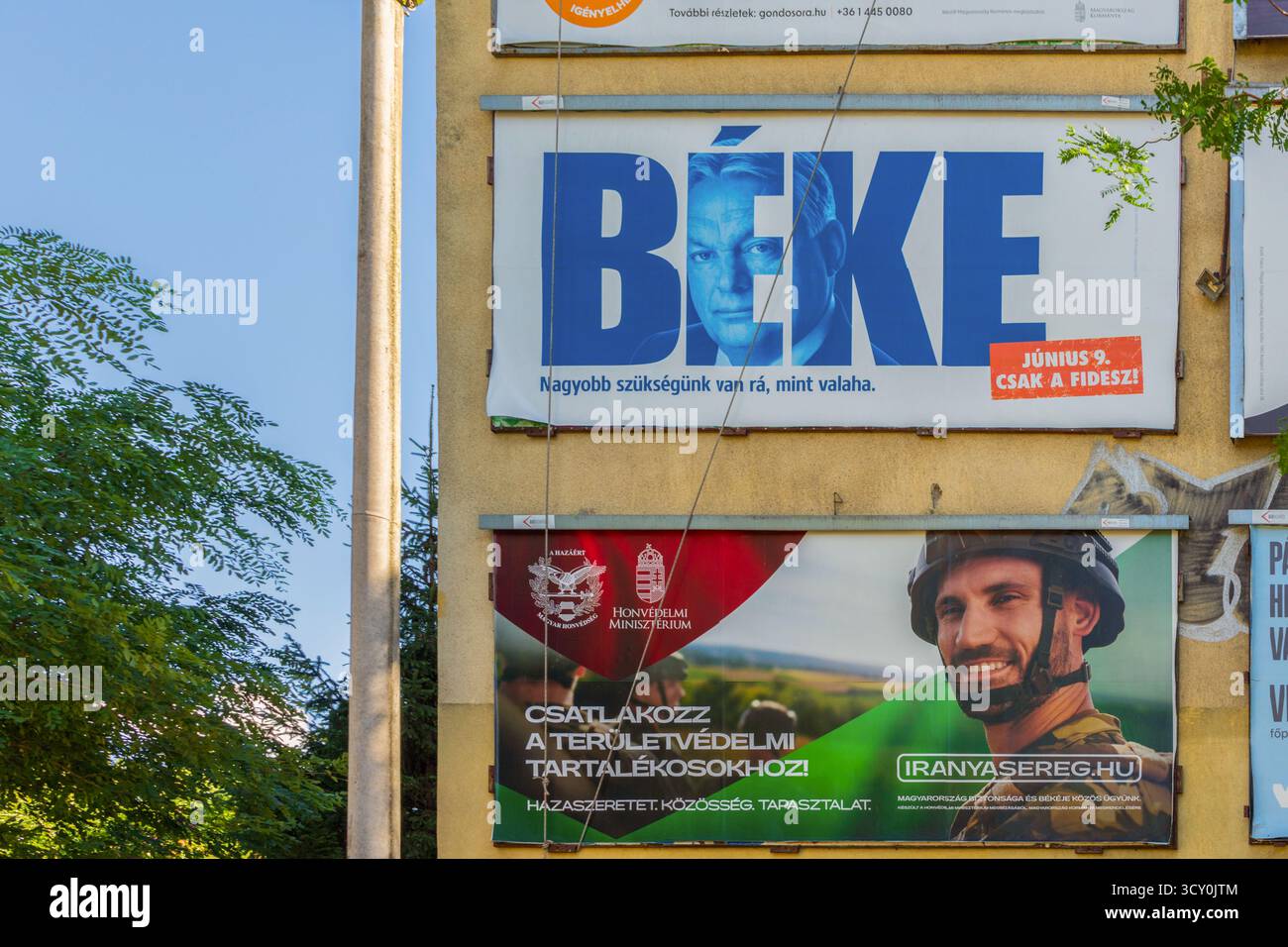 Un display a doppio messaggio: Il cartellone Fidesz dichiara “PACE”, mentre l’attiguo cartellone del Ministero della difesa esorta a “ADERIRE ALLA DIFESA TERRITORIALE”. Foto Stock