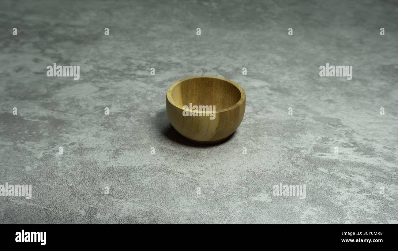 Recipiente singolo in legno su sfondo grigio, elemento rustico minimalista per alimenti con consistenza organica e toni neutri delicati per l'uso culinario o di design Foto Stock
