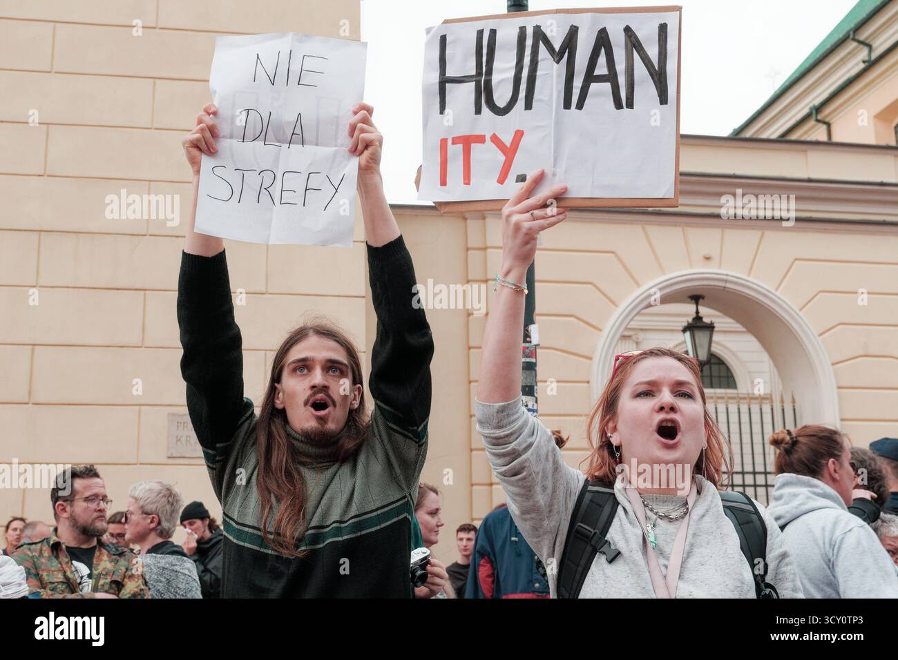Giovani uomini e donne che protestano contro la creazione di una zona cuscinetto vicino al confine polacco-bielorusso, urlano e tengono cartelli. Foto Stock