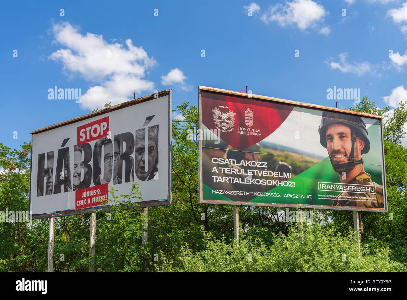 Due manifesti contrastanti a Budapest: Uno avverte “Stop War!”, l’altro invita i cittadini ad unirsi alla difesa territoriale, mostrando due storie. Foto Stock
