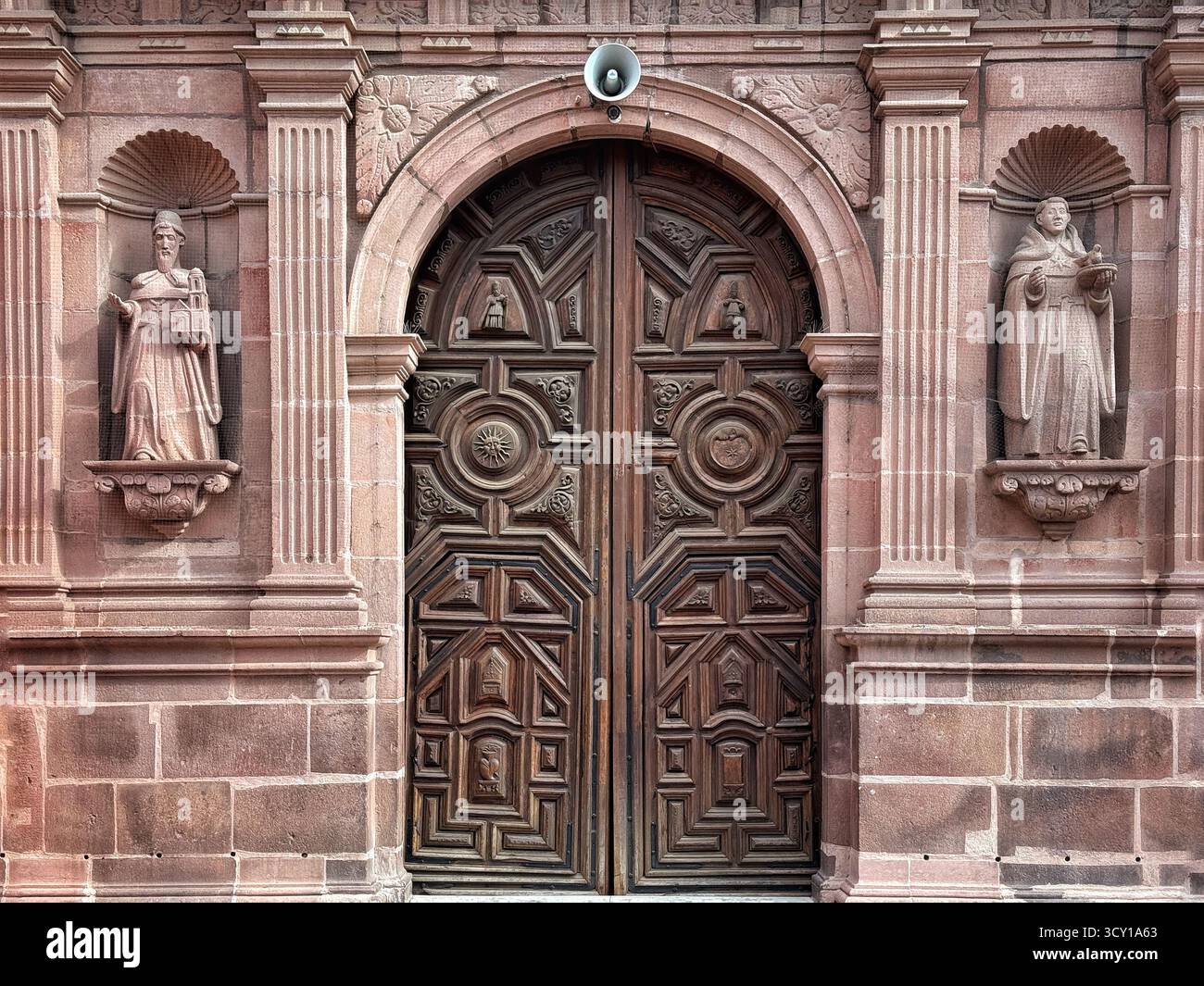 Porta ornata in legno dello storico edificio in pietra a San Luis Potosi, MX fiancheggiata da 2 statue in nicchie intagliate, caratterizzate da intricati dettagli architettonici Foto Stock