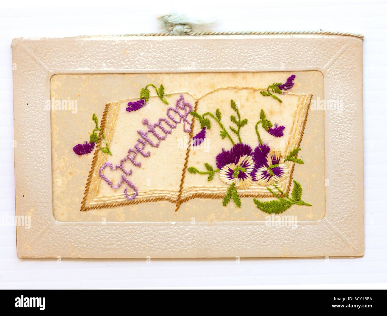 WW! Cartolina di Natale ricamata in seta. "Greetimgs" sulla pagina di un libro aperto. Foto Stock