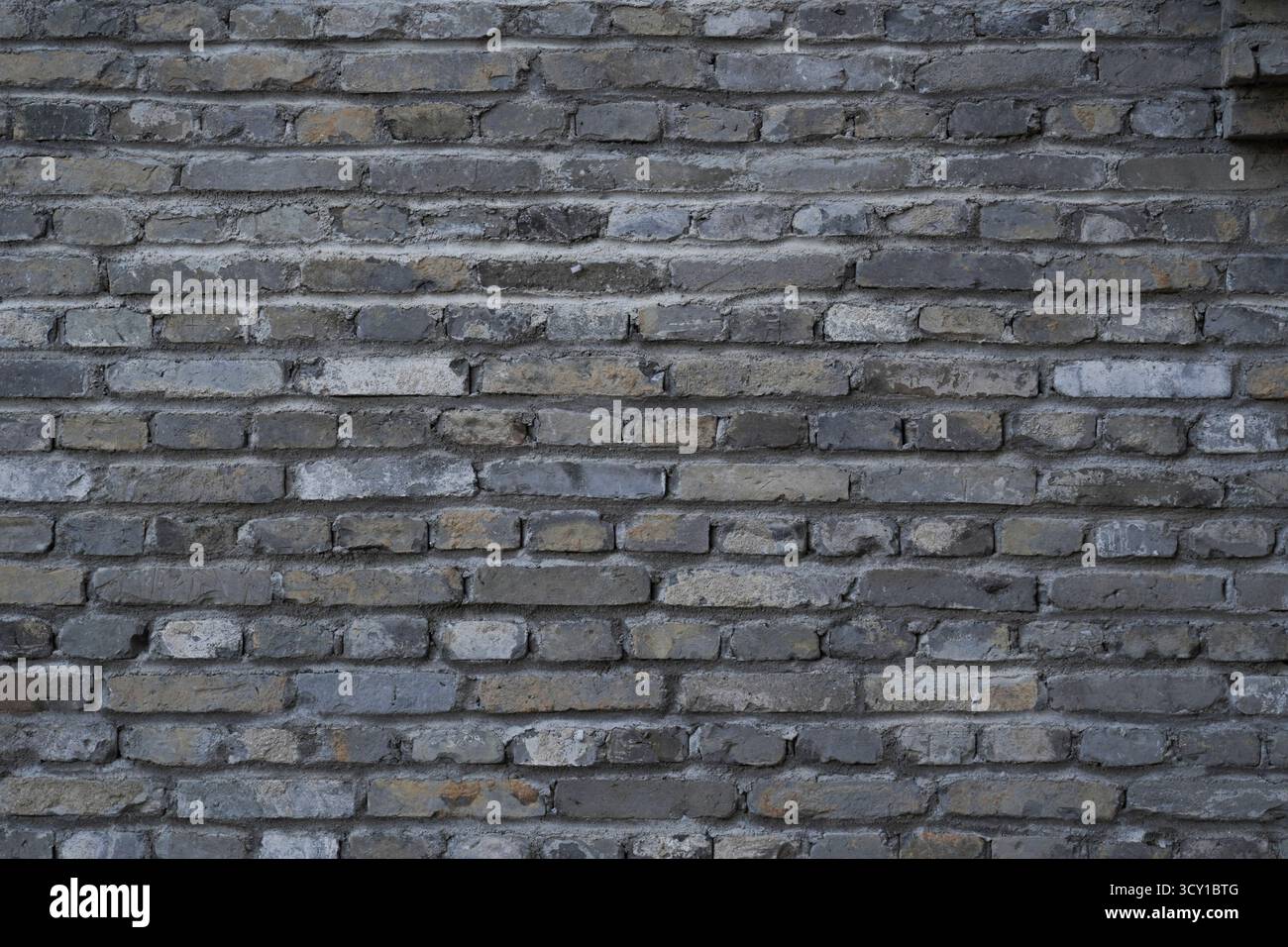 Una parete in mattoni grigi con superficie ruvida Foto Stock