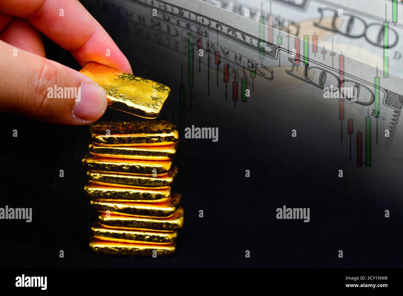Mano che tiene in mano una barra d'oro il grafico delle candele e lo sfondo del dollaro statunitense , le fluttuazioni del concetto di prezzo dell'oro. Foto Stock