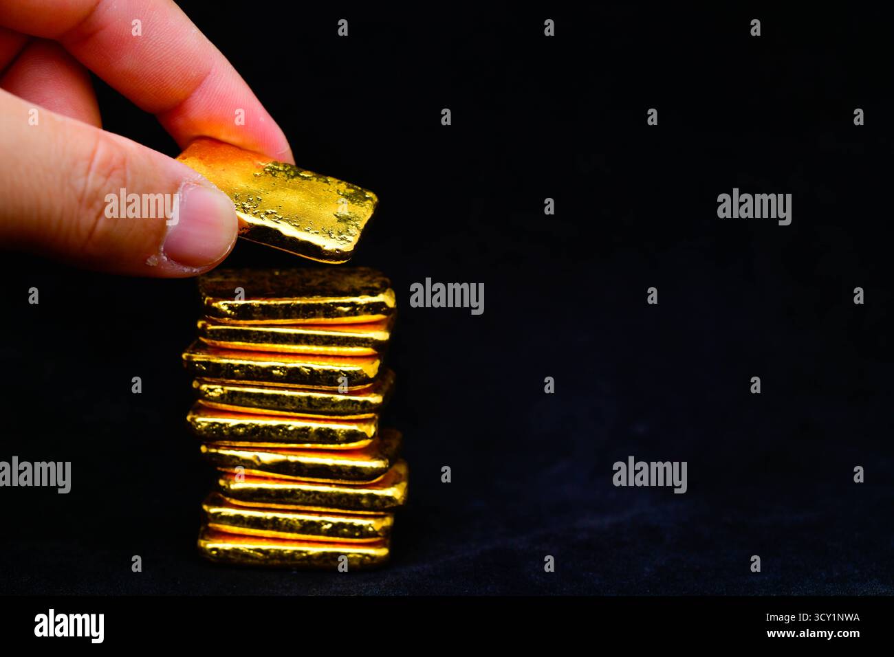 Primo piano della mano con barre dorate su sfondo nero Foto Stock