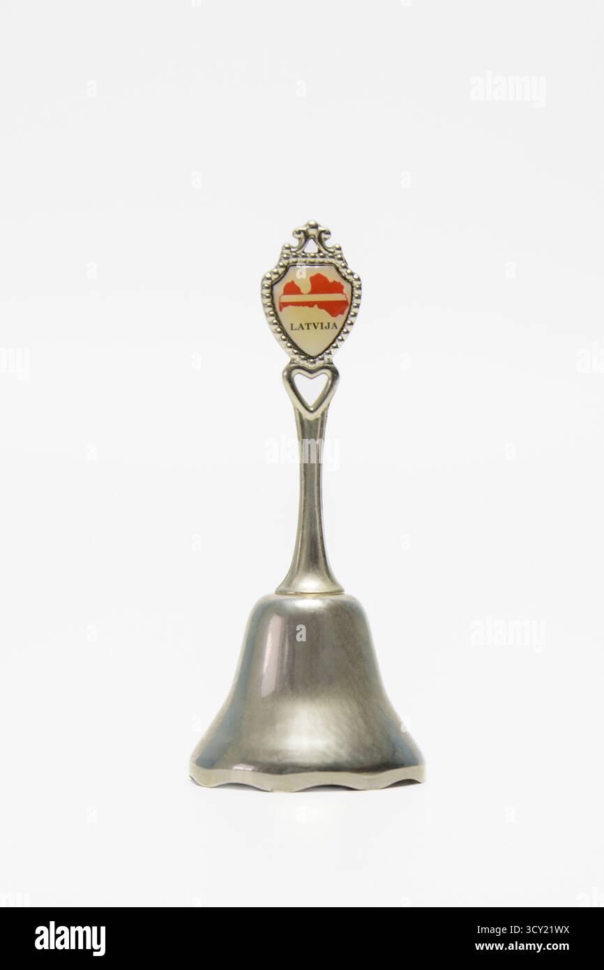 Hasselt. Limburgo - Belgio 13-03-2024. Piccola campana in metallo ricordo con motivi e incisioni. Iscrizione Lettonia. Su sfondo bianco Foto Stock
