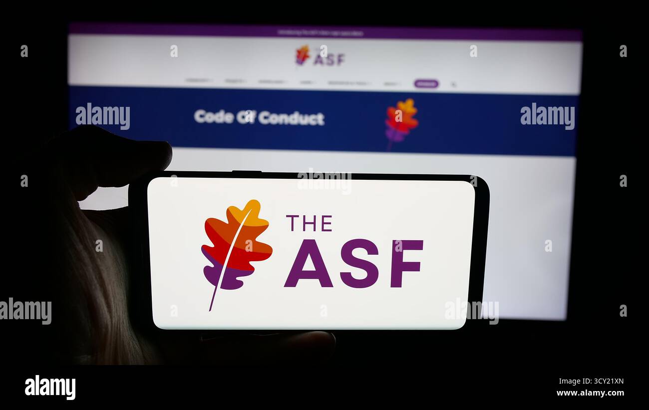 In questa immagine, una persona ha in mano un cellulare con il logo dell'organizzazione Apache software Foundation (ASF) sullo schermo davanti alla pagina Web. Foto Stock