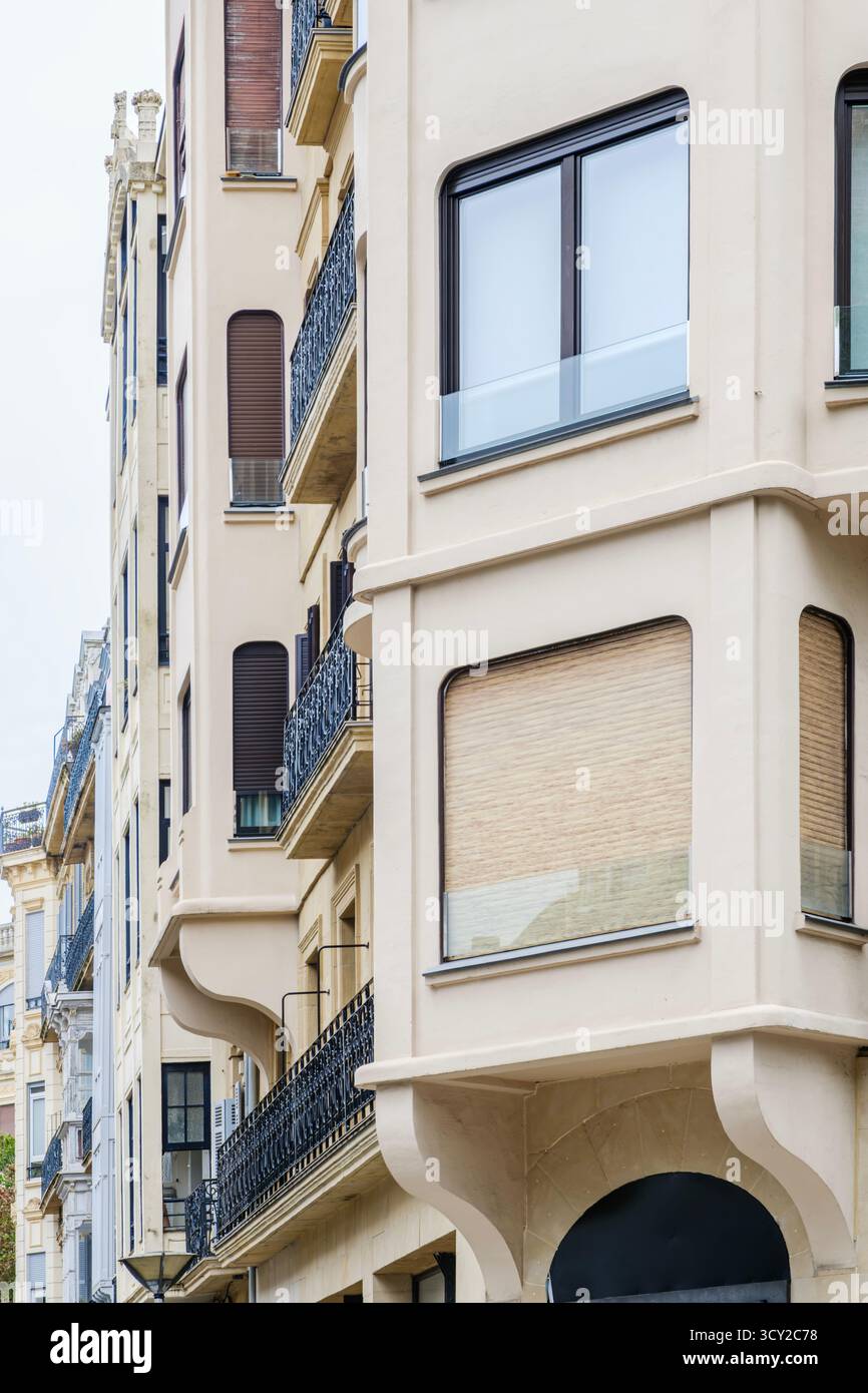 Dettagli ravvicinati di una moderna facciata urbana caratterizzata da pareti beige lisce e finestre con angoli arrotondati, che contrastano nettamente con il tradizionale wroug Foto Stock