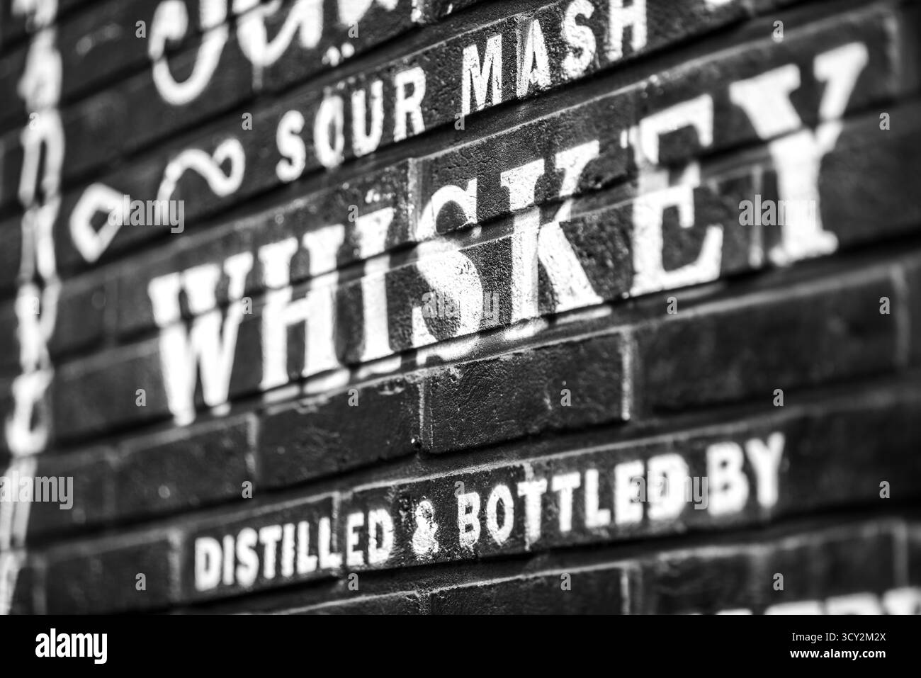 Immagine in bianco e nero di un muro di mattoni con testo dipinto che pubblicizza whiskey in bar Street nel quartiere di Itaewon a Seoul, Corea del Sud, l'11 novembre 202 Foto Stock