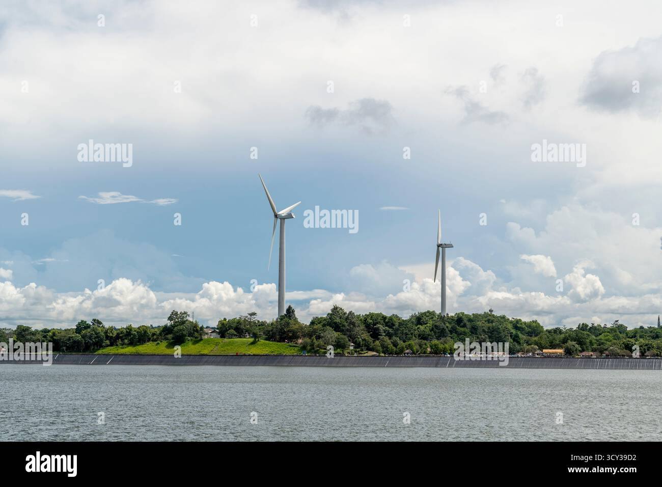 La tecnologia energetica sostenibile, che utilizza grandi turbine eoliche, genera energia pulita su una lussureggiante cresta di montagna verde in Asia. La scena, sotto un clou in parte Foto Stock