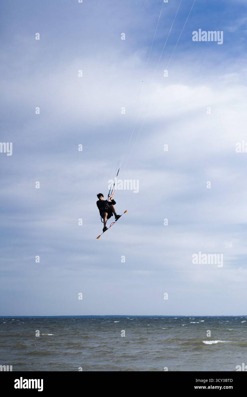 Kiteboarder che esegue un salto aereo con la tavola sopra l'acqua Foto Stock
