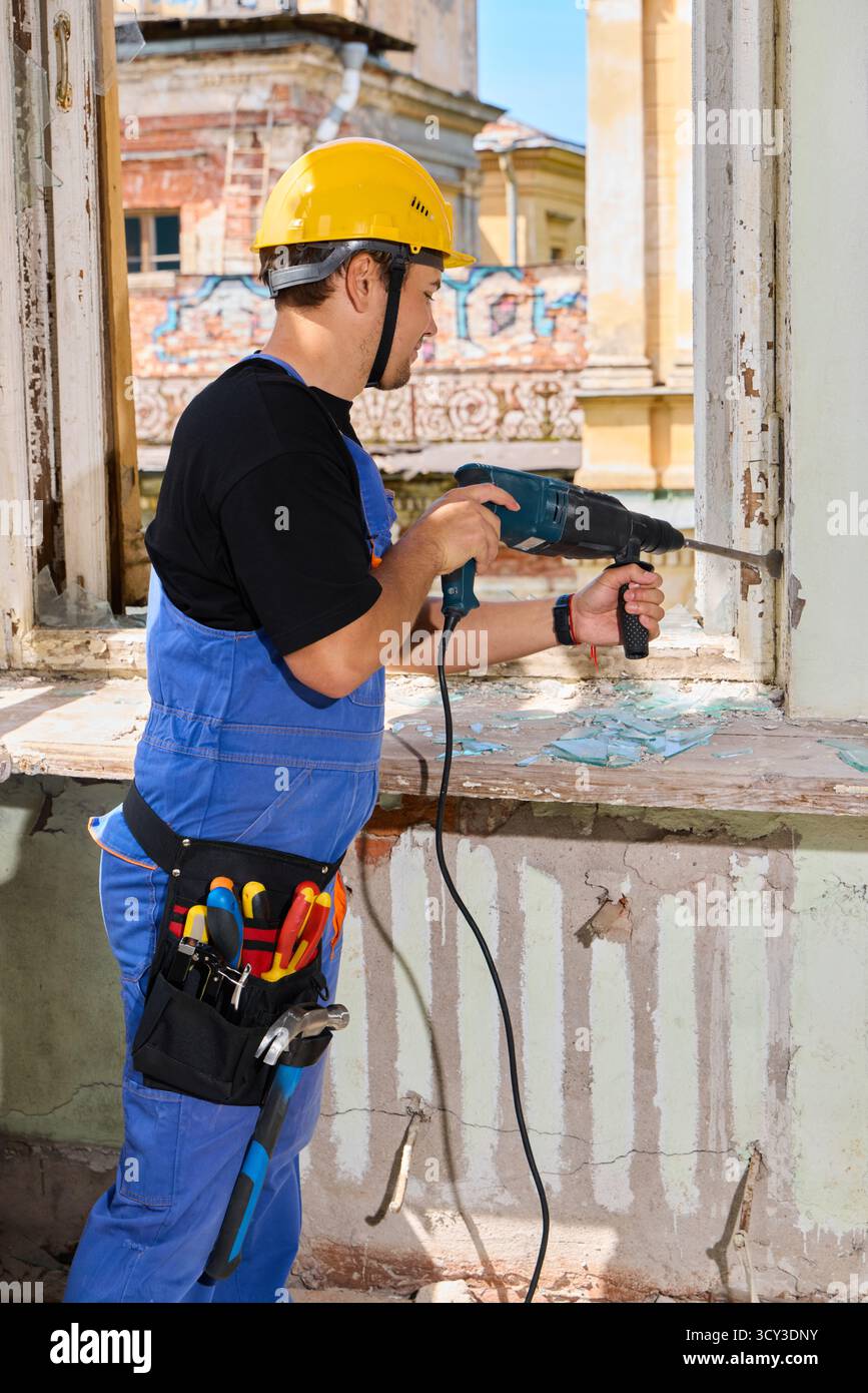 Il lavoratore ripara una finestra in un vecchio edificio durante il giorno Foto Stock