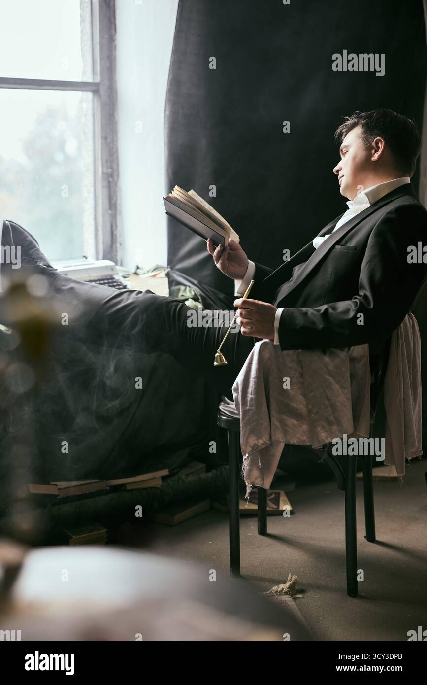 Uomo elegante che legge in una camera elegante con arredamento scuro Foto Stock