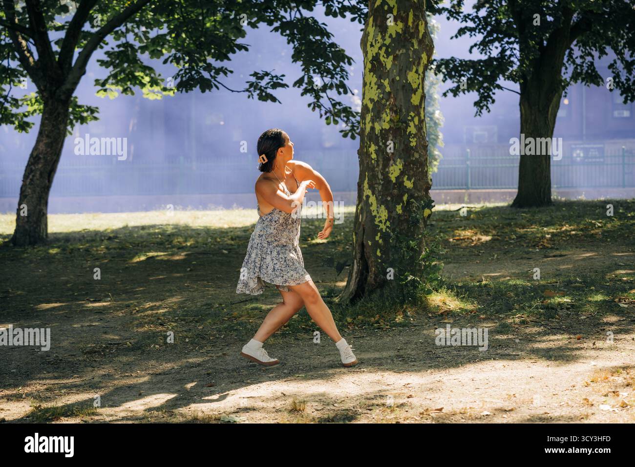 Donna che danzava con spettacolo contemporaneo con fumo viola nel parco Foto Stock