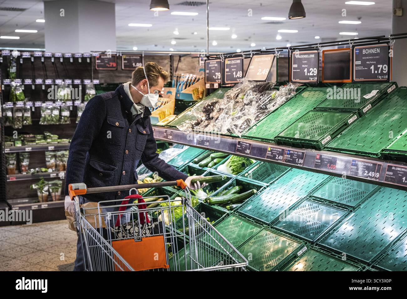 DEU Germany Germany Berlin Shoppers che indossano maschere protettive presso uno stand di frutta in un supermercato Foto Stock