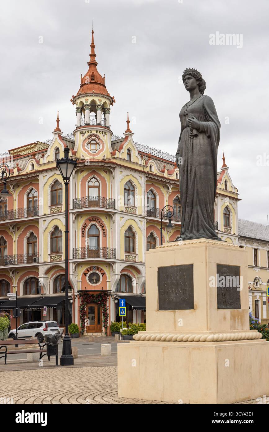 Oradea, Romania - 26 settembre 2025: Scultura della regina Maria Regina Romaniei (Marie van Edinburgh) di fronte all'Art nouveau Grant hotel Astoria in OR Foto Stock