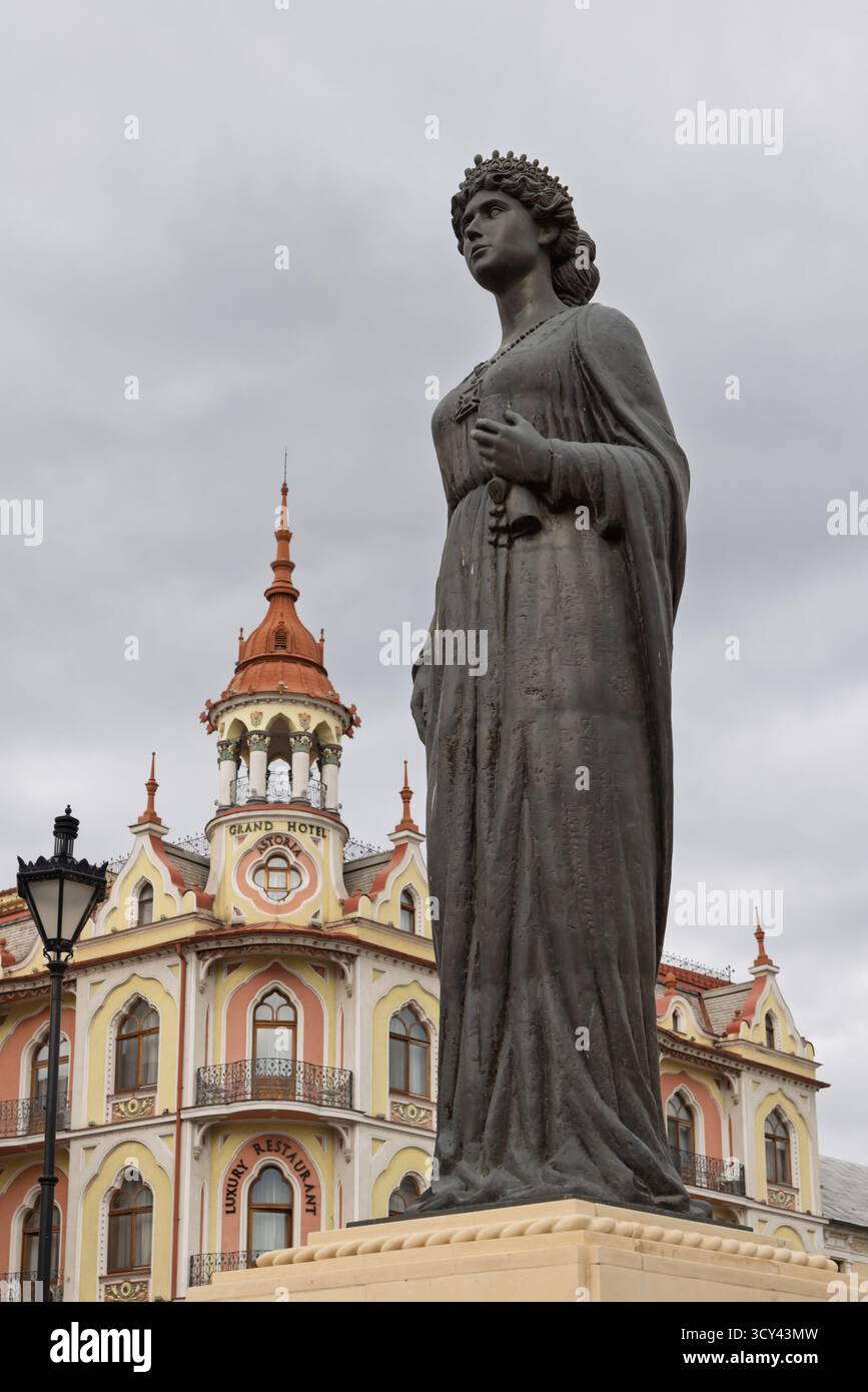 Oradea, Romania - 26 settembre 2025: Scultura della regina Maria Regina Romaniei (Marie van Edinburgh) di fronte all'Art nouveau Grant hotel Astoria in OR Foto Stock